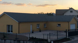 Maison moderne jaune avec toit gris au coucher ou lever du soleil chez Vaxelaire Rémi.